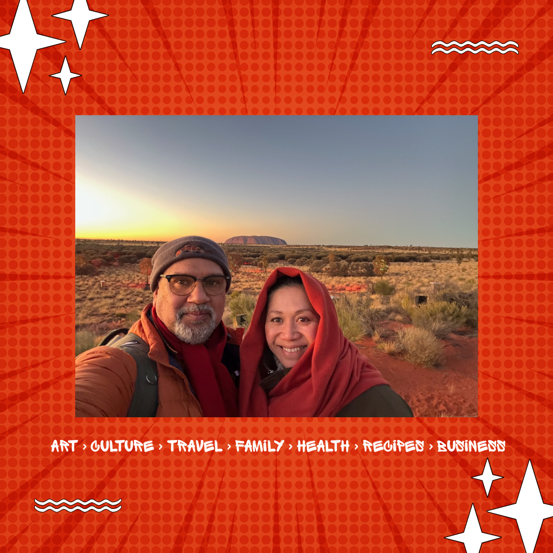 Mark Yettica-Paulson and Maryann Talia Pau smiling together at Uluru during sunset, wrapped in warm scarves, celebrating culture, travel, and connection for Damper & Fetū blog.